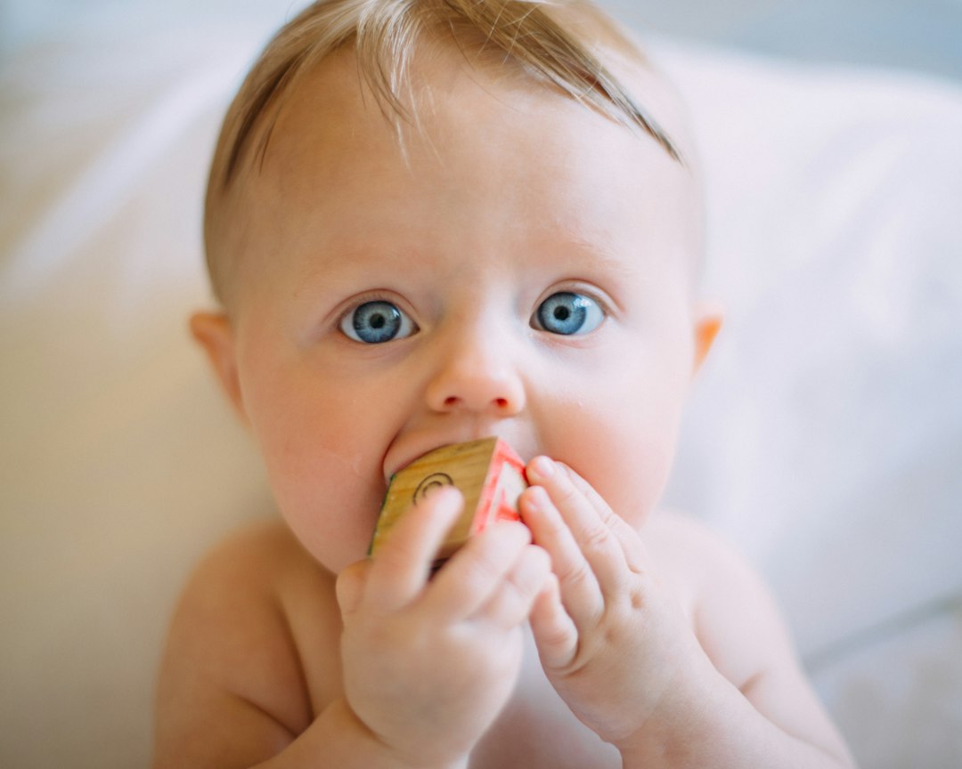 Baby Toys by Dream and Meaning selective focus photography of baby holding wooden cube
