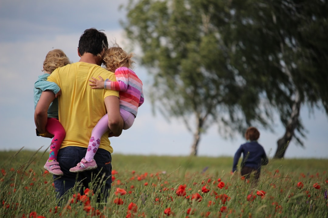 Heading home before the storm by Dream and Meaning man carrying to girls on field of red petaled flower