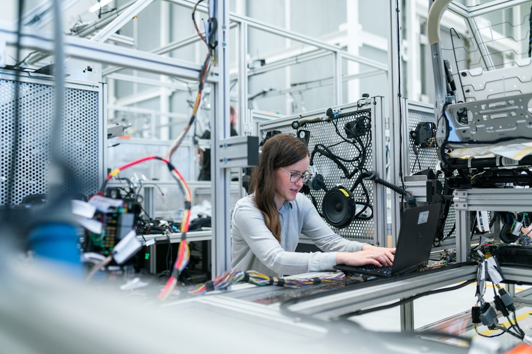 Female electronics engineer runs vehicle tests by Dream and Meaning woman in white long sleeve shirt using black laptop computer
